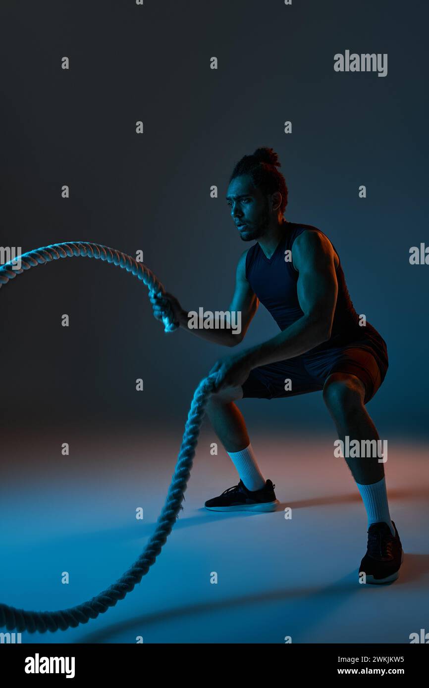 attractive young african american man in black sport uniform training actively with battle ropes Stock Photo