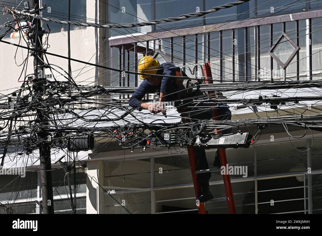 Elektriker auf einer Leiter arbeitet an der massiven Verkabelung im Stadtteil Roma, Mexiko Stadt Stock Photo