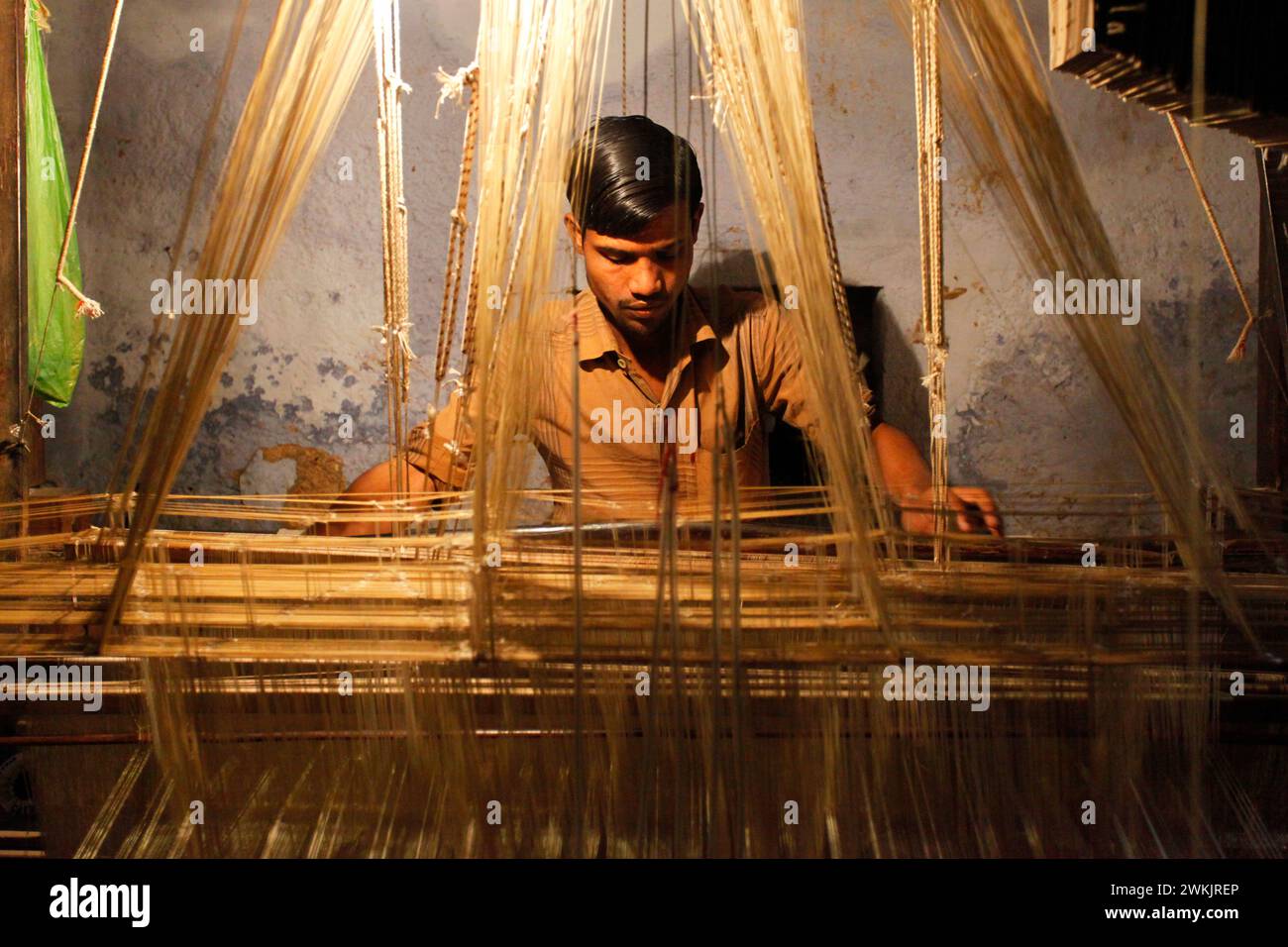 An artisan silk weaver working in a textile workshop in Varanasi, Uttar Pradesh, India. Stock Photo