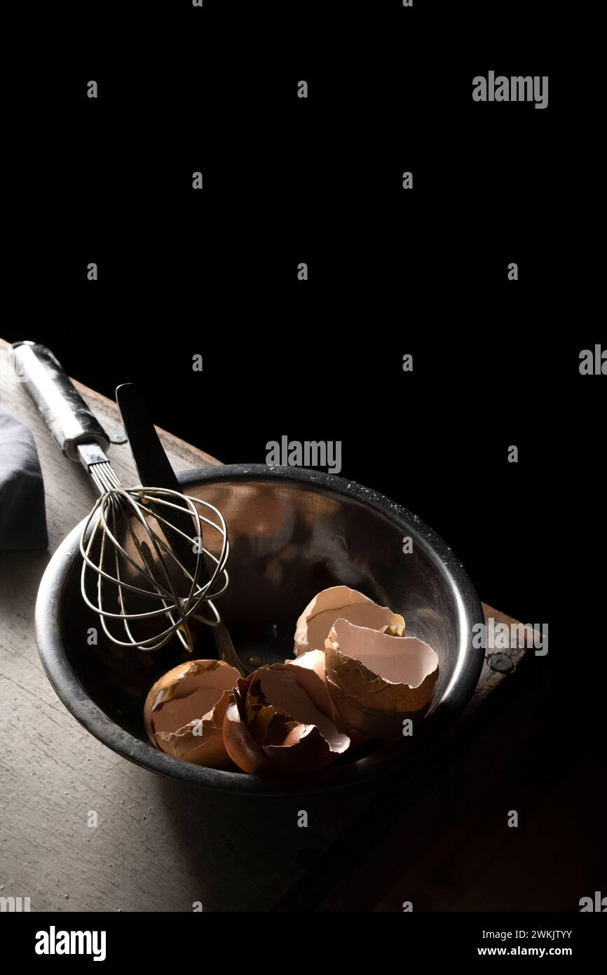 Cracked eggshells and whisk on the table, space for text Stock Photo