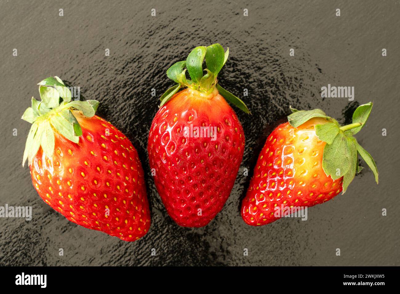 Three strawberries on black reflective background Stock Photo - Alamy