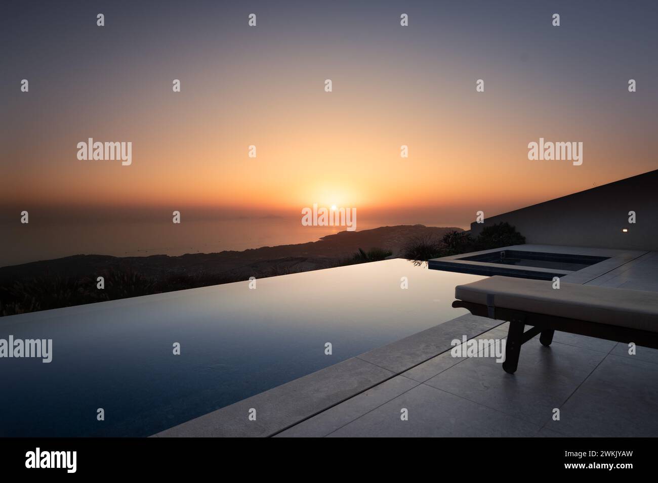 Twilight Serenity: Sun Setting Over Ocean View Pool Stock Photo