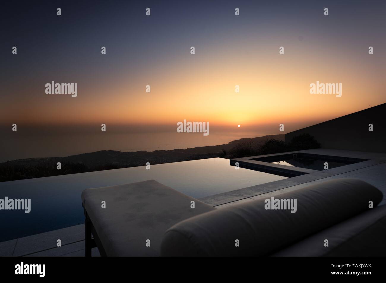 Twilight Serenity: Sun Setting Over Ocean View Pool Stock Photo