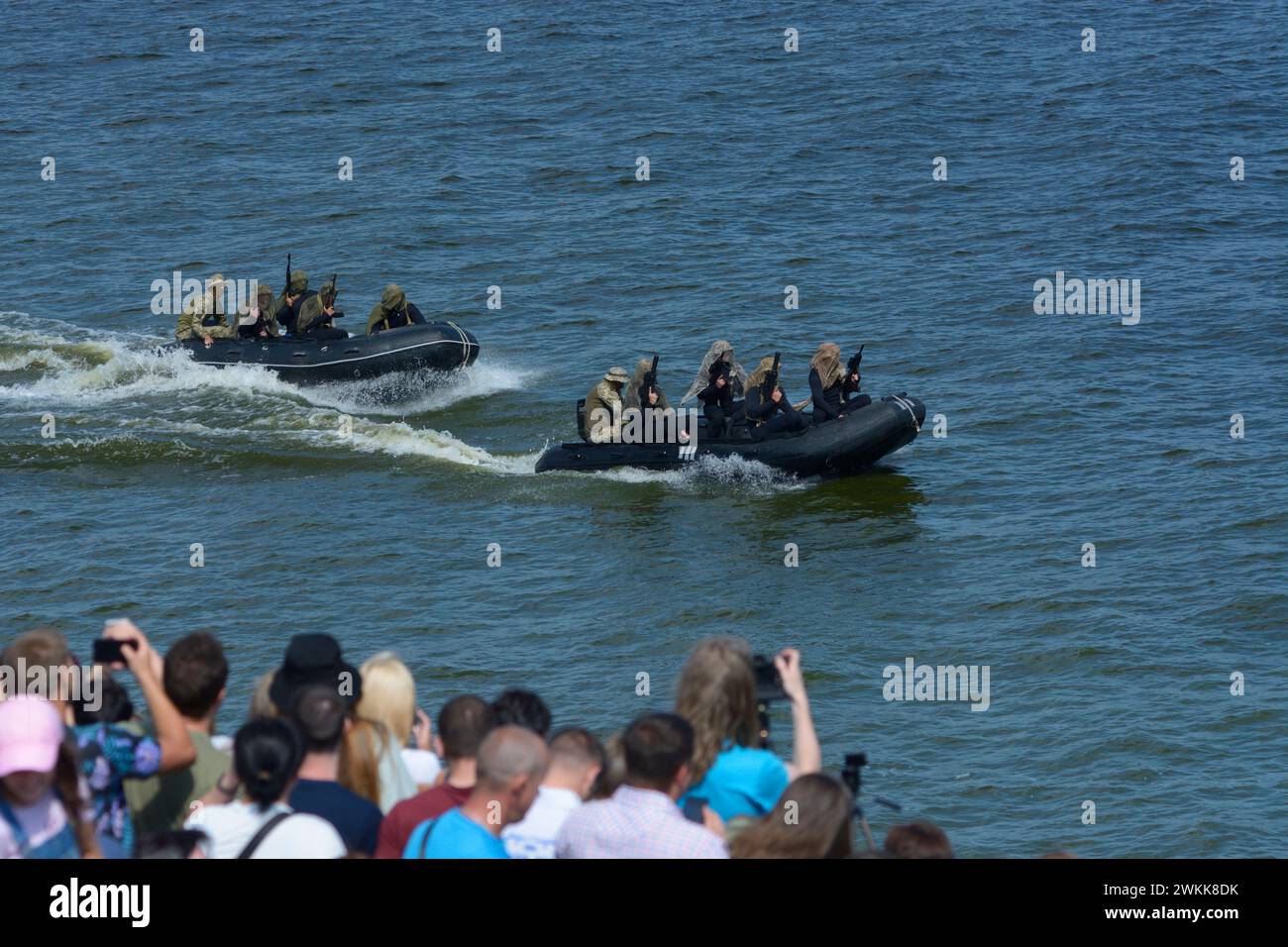 Military boats floating on water, armed soldiers of Special Forces aboard, crowd of people watching. August 24, 2021. Military parade to the Independe Stock Photo