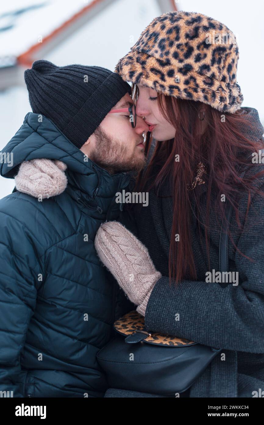 Fashion pretty young couple in fashionable winter clothes sit together ...