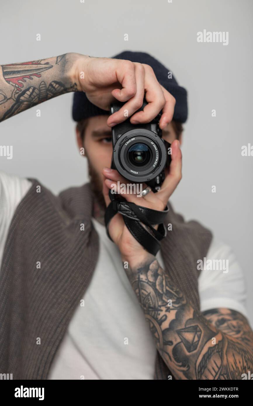 Handsome man professional photographer holding photo camera and taking pictures on white background in the studio Stock Photo