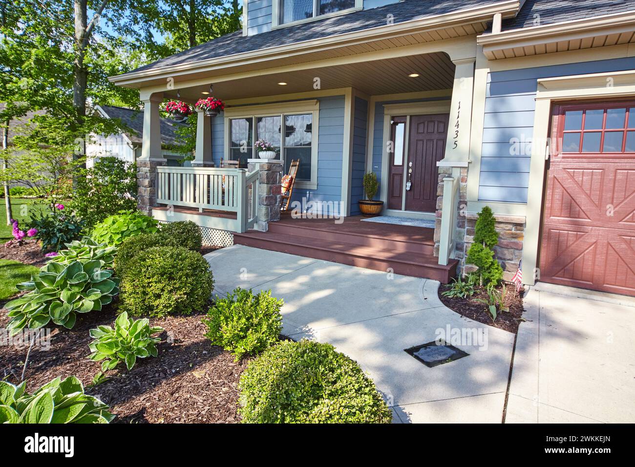 Sunlit Suburban Home with Front Porch and American Flag Stock Photo