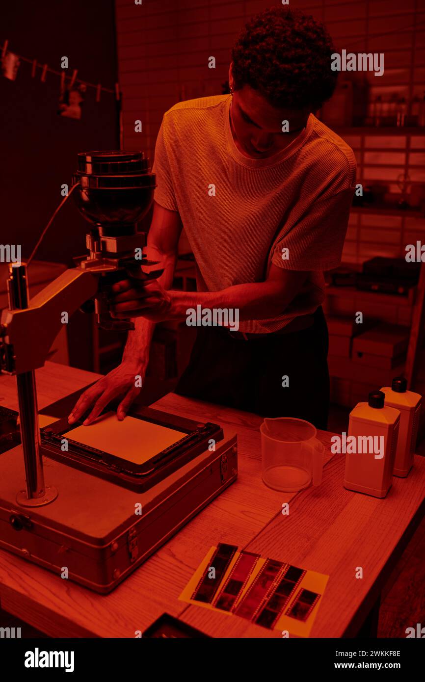 dark skinned photographer focuses on delicate process of enlarging film