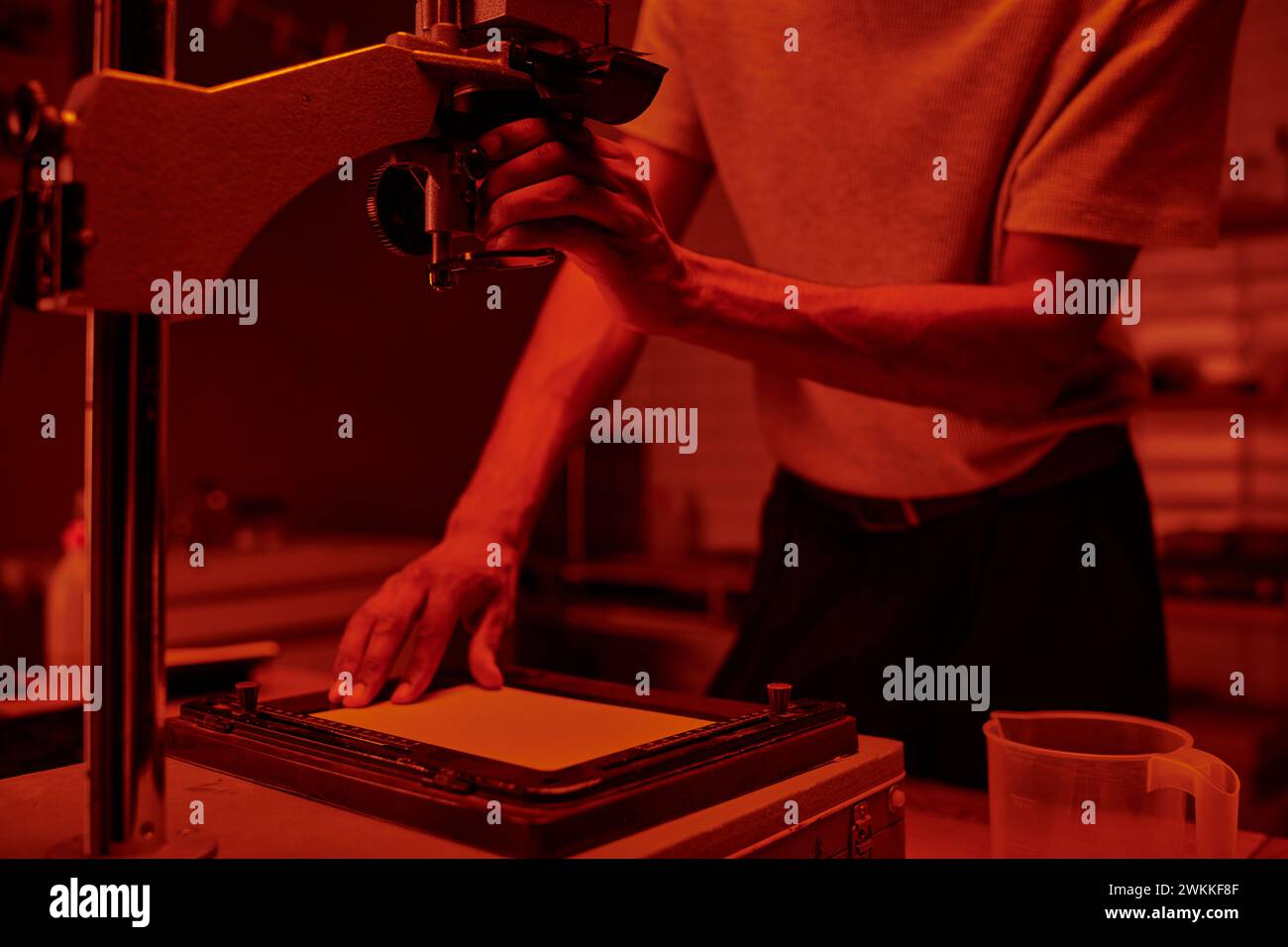 cropped photographer focuses on delicate process of enlarging film in