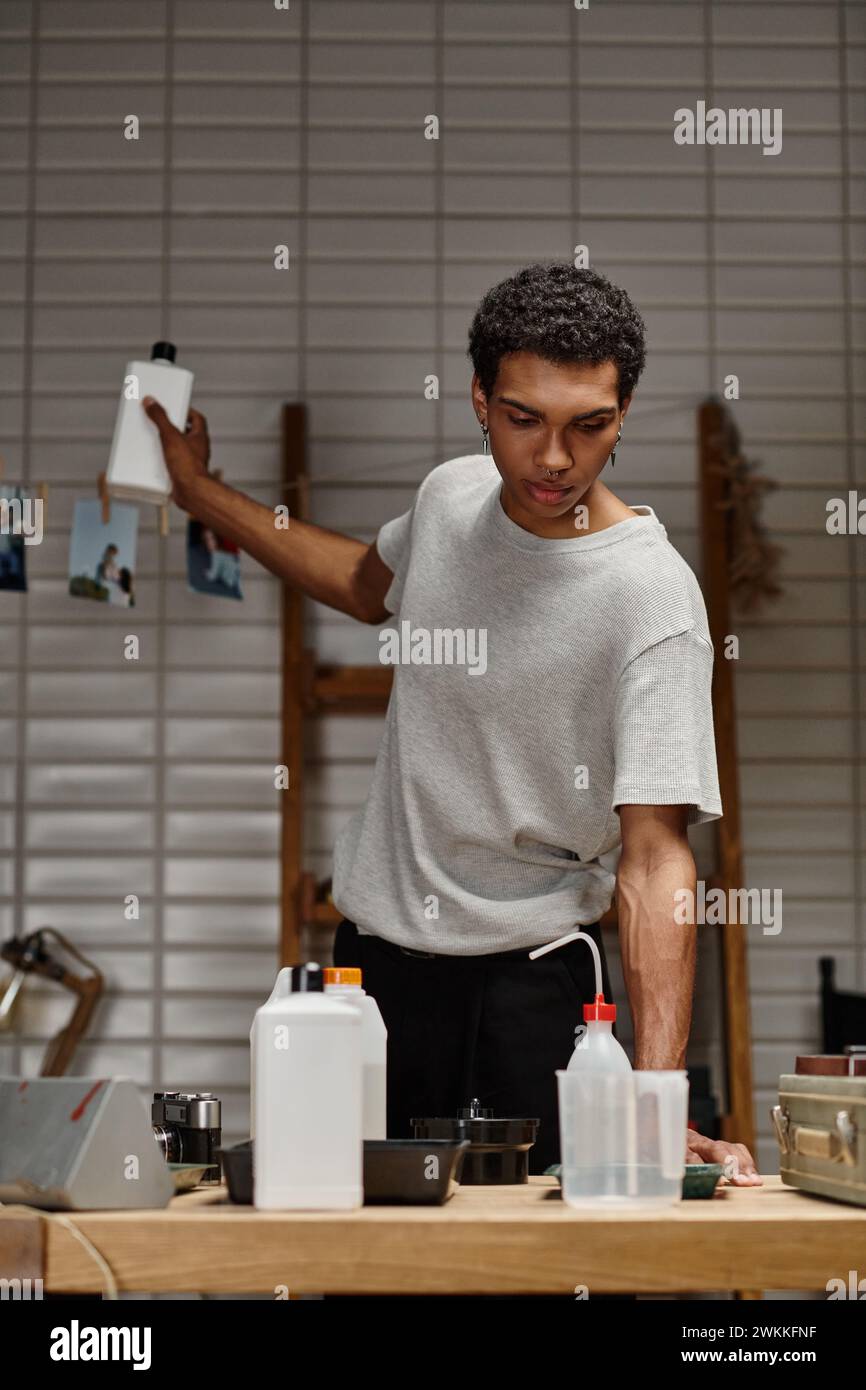 young african american guy choosing chemical solution in darkroom, film