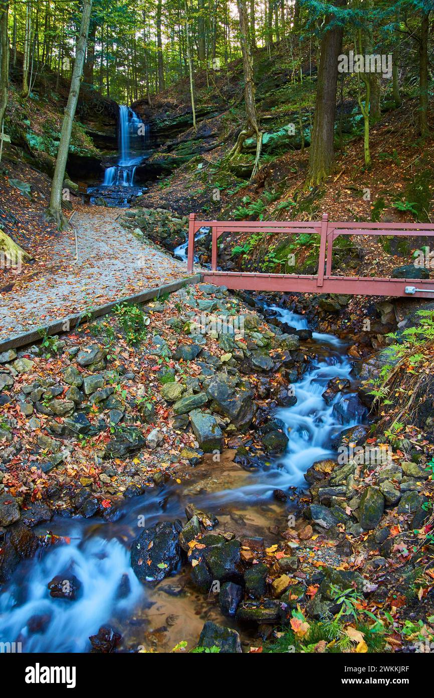 Autumn Waterfall and Rustic Bridge in Woodland Scene Stock Photo