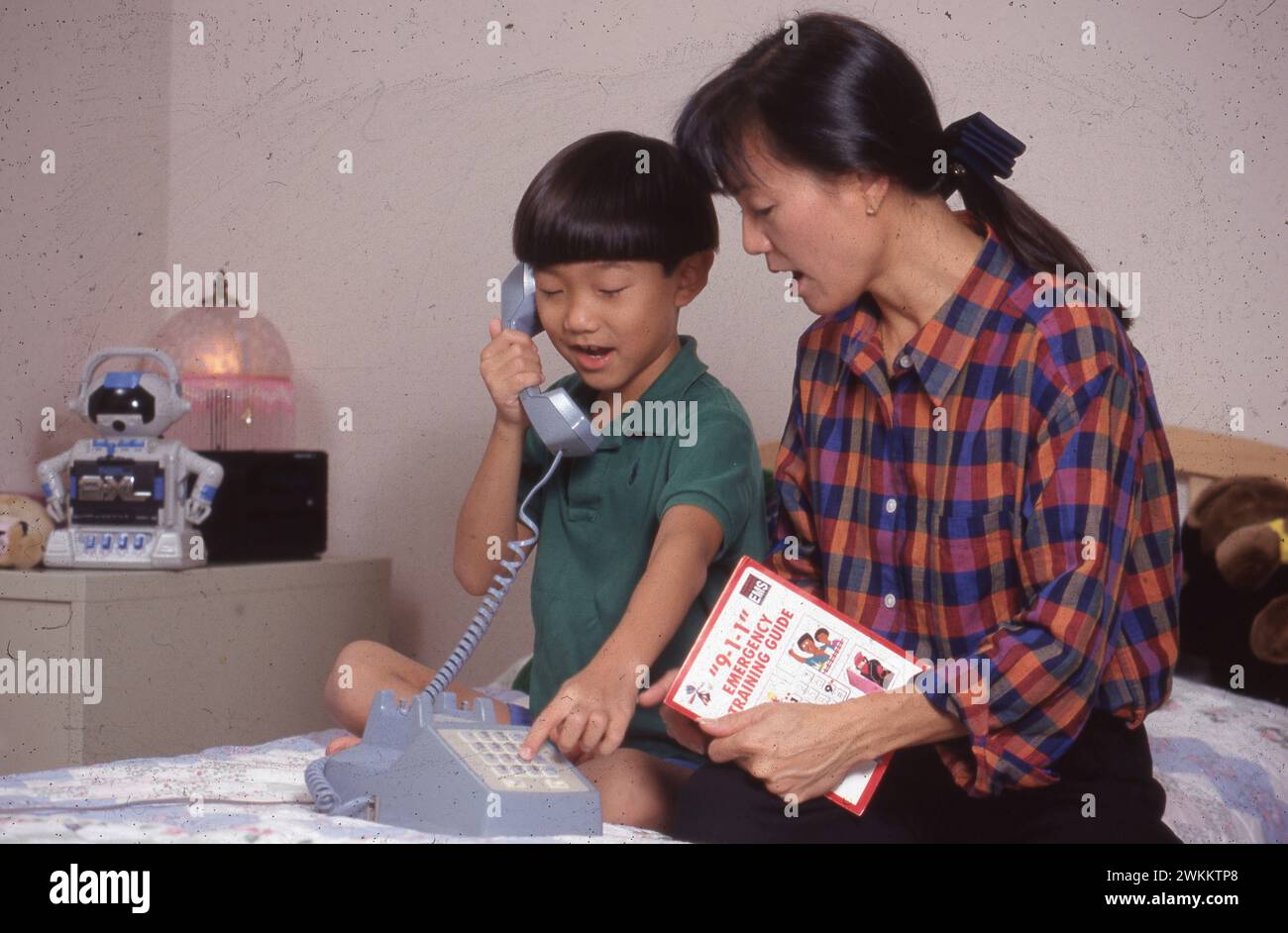 Asian-American mother helps her 7-year-old son practice calling the 9-1-1 emergency number. ©Bob Daemmrich Stock Photo
