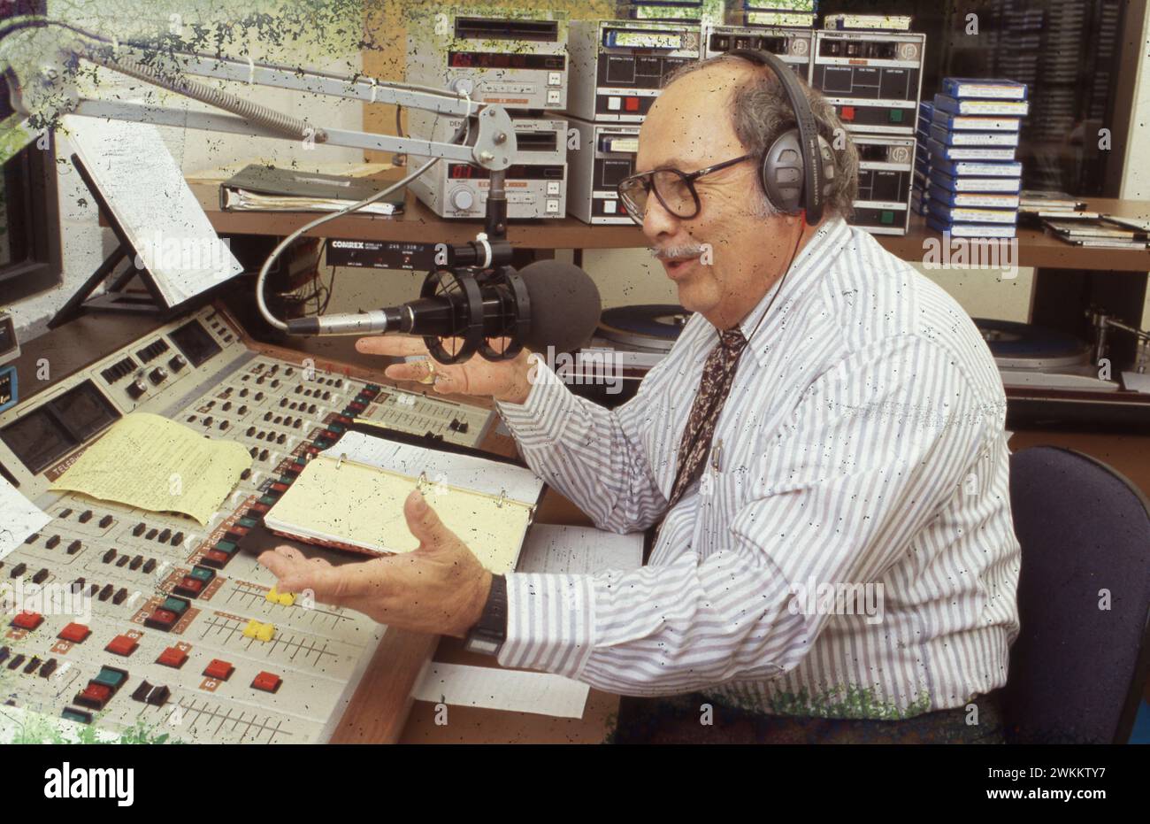 San Antonio Texas USA, 1991: Hispanic radio disc jockey wearing headphones talks into microphone while broadcasting show from control room of Spanish-language radio station KCOR. ©Bob Daemmrich Stock Photo