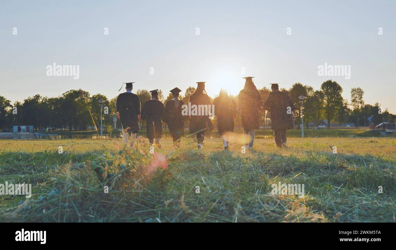 Graduate students walking through an evening meadow at sunset. Stock Photo