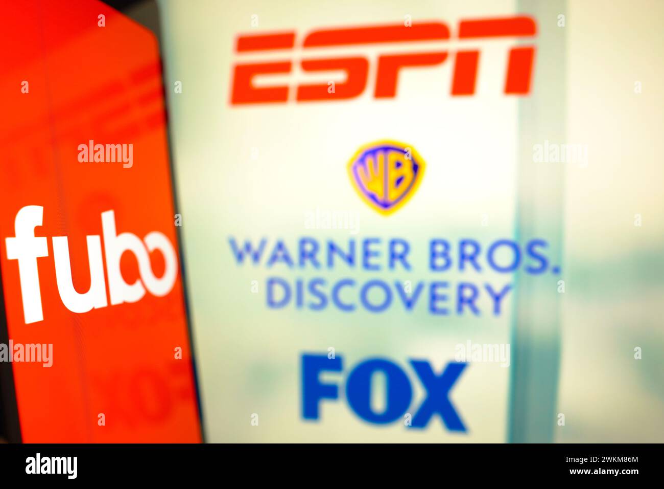 In this photo illustration, the FuboTV Inc. logo is displayed on a smartphone screen and ESPN, Warner Bros. Discovery and FOX logos in the background. Stock Photo
