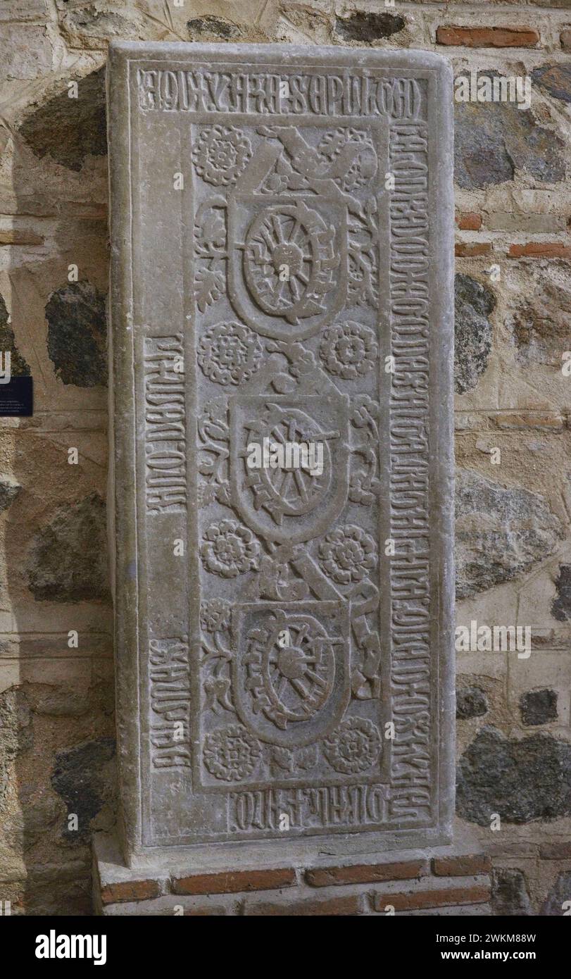 Tombstone of Diego de Santa Catalina. Vegetal decoration. In the central part, shields depicting the 'Catherine Wheel', instrument with which St. Catherine (Santa Catalina) was executed by order of Emperor Maximian. Inscriptions in capital Gothic characters in the border. Stone. 14th century. From the Church of San Román. Toledo, Spain. Museum of Visigoth Councils and Culture. Toledo, Castile-La Mancha, Spain. Stock Photo