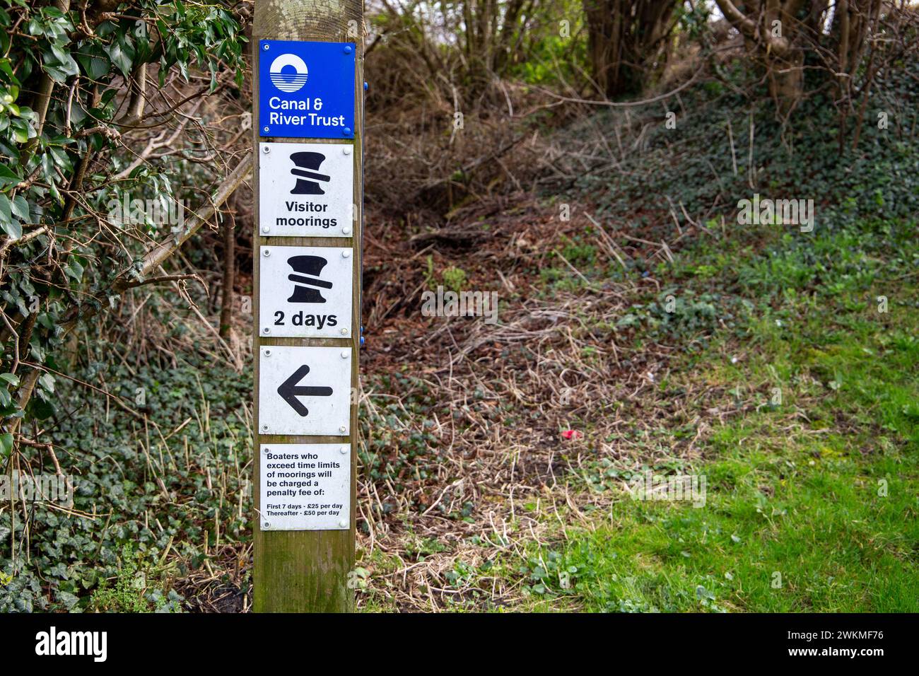 Visitor moorings signpost by the Canal & River Trust indicating a 2-day limit, set against natural foliage. Stock Photo