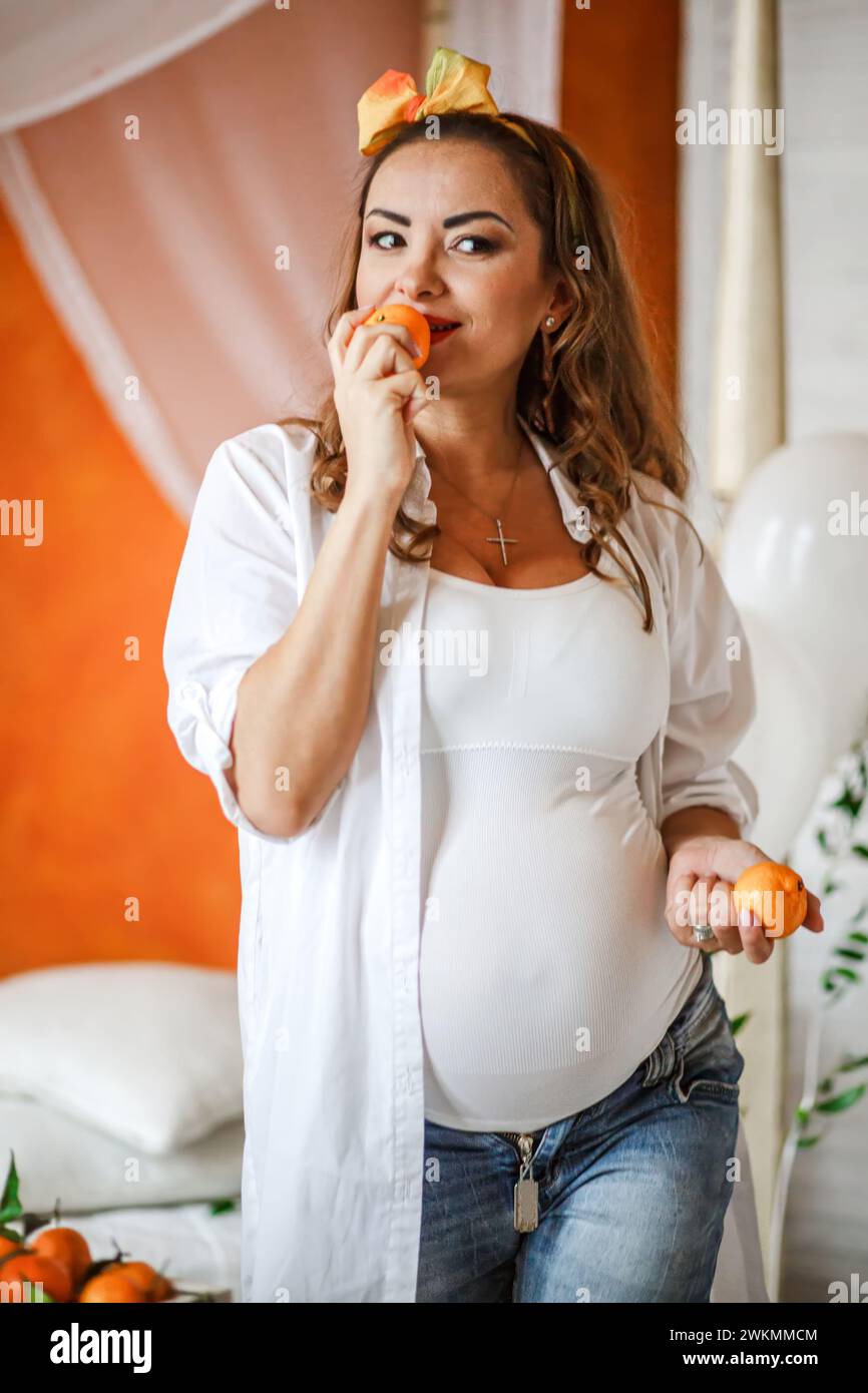 Pregnant woman eating tangerines in her bedroom at home. Healthy eating