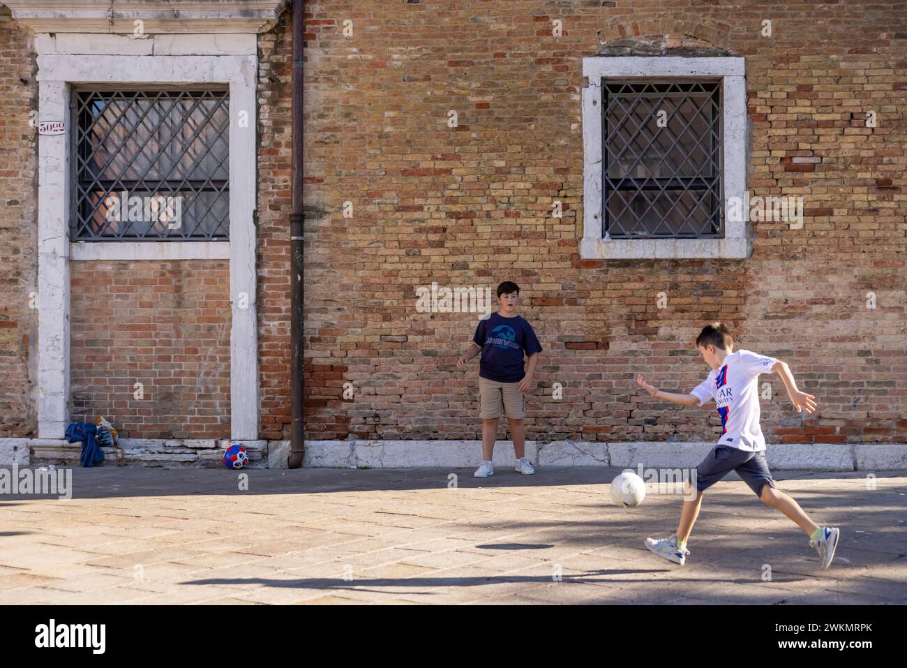 A group of kids play soccer in a town square in Venice, Italy. Stock Photo