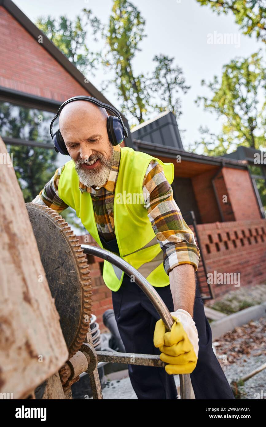handsome cheerful man in safety gloves and headphones working with