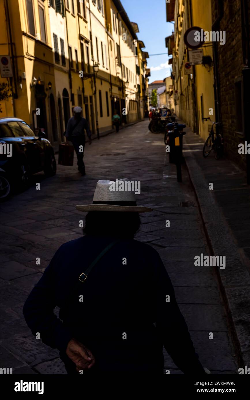 A woman in a fedora walks down a street in Florence, Italy, the Renaissance capital of the world. Stock Photo