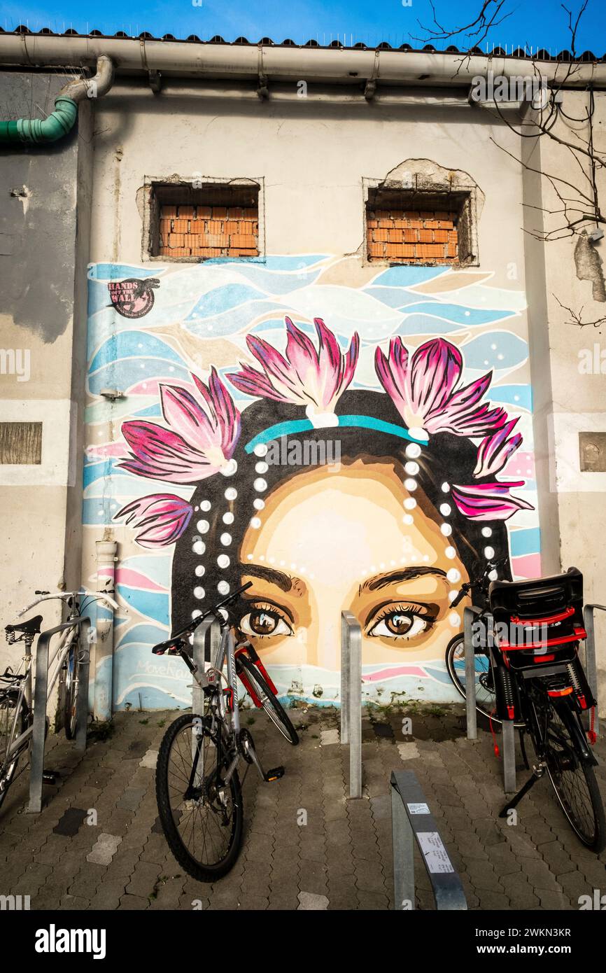 Bikes locked up next to a colorful mural of a woman in the Werksviertel neighborhood of Munich, Germany Stock Photo