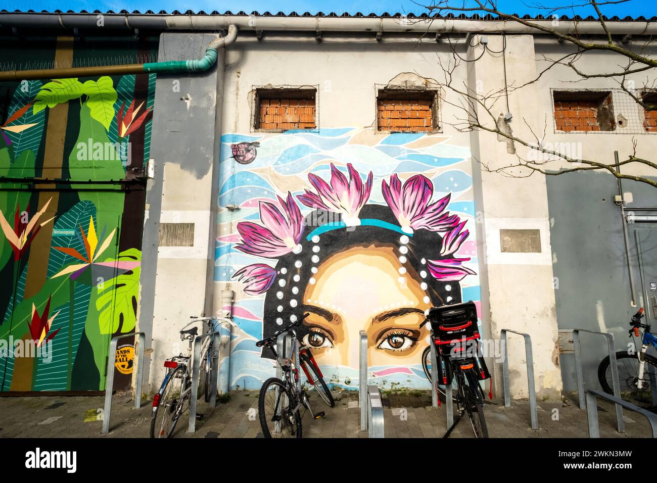 Bikes locked up next to a colorful mural of a woman in the Werksviertel neighborhood of Munich, Germany Stock Photo