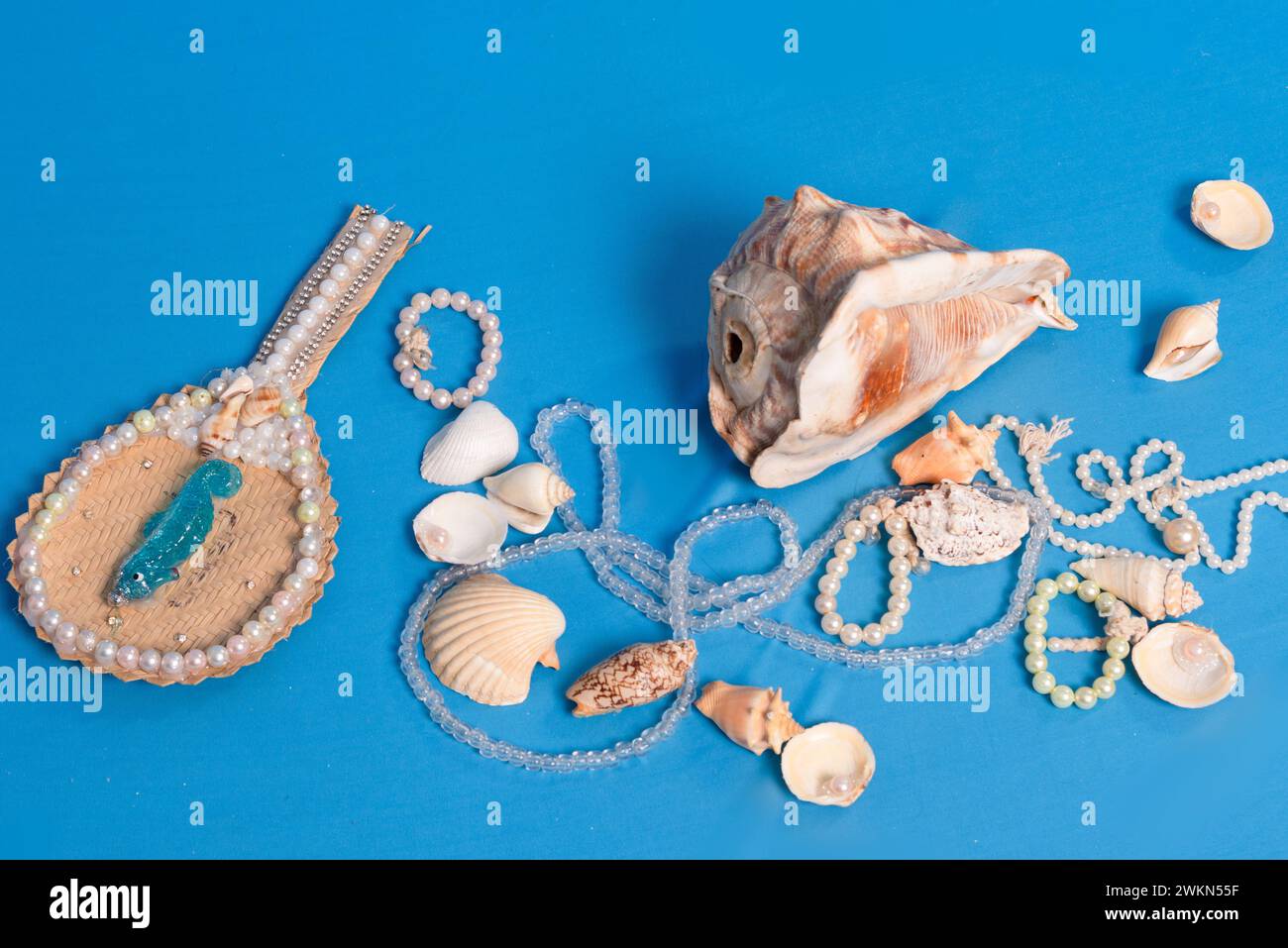 Several sea shells, necklaces and mirror scattered on the blue studio floor. Tribute to iemanja. Stock Photo