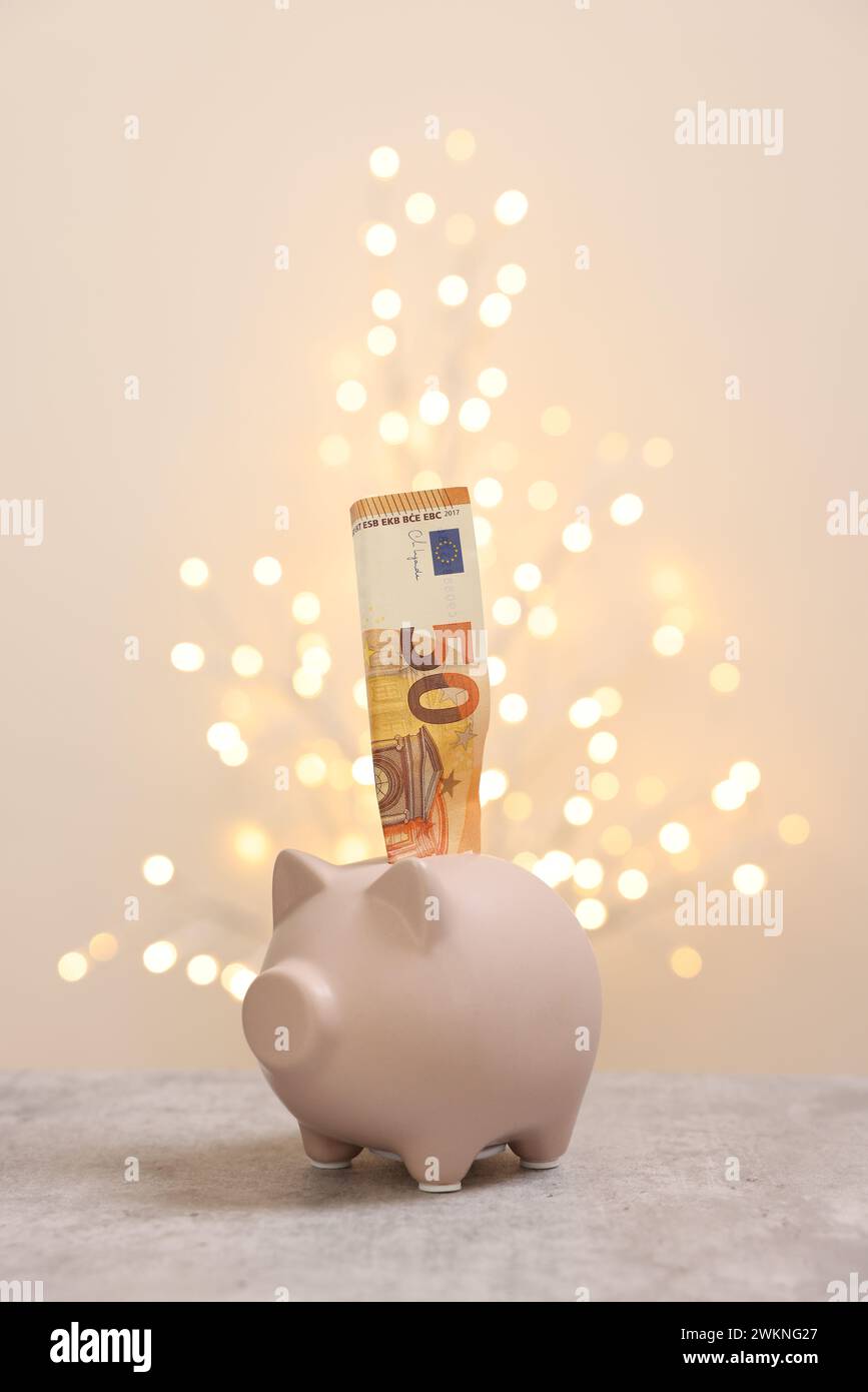 Piggy bank with euro banknote on grey table against blurred lights ...