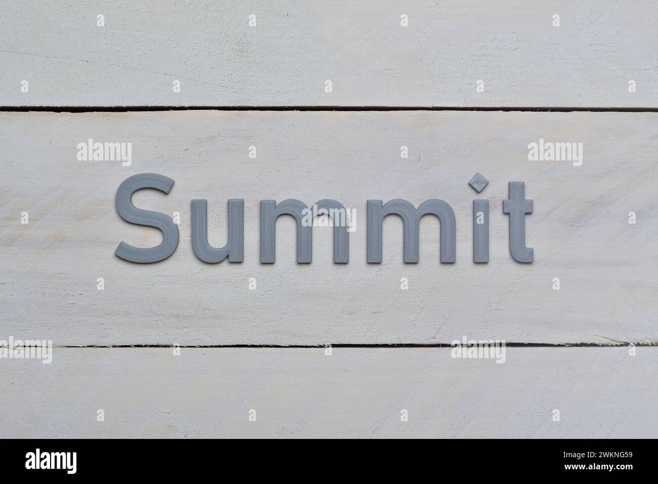 Grey Summit letters printed in 3D. Target to reach message. Letters presented on rough whitish wood board background. Stock Photo