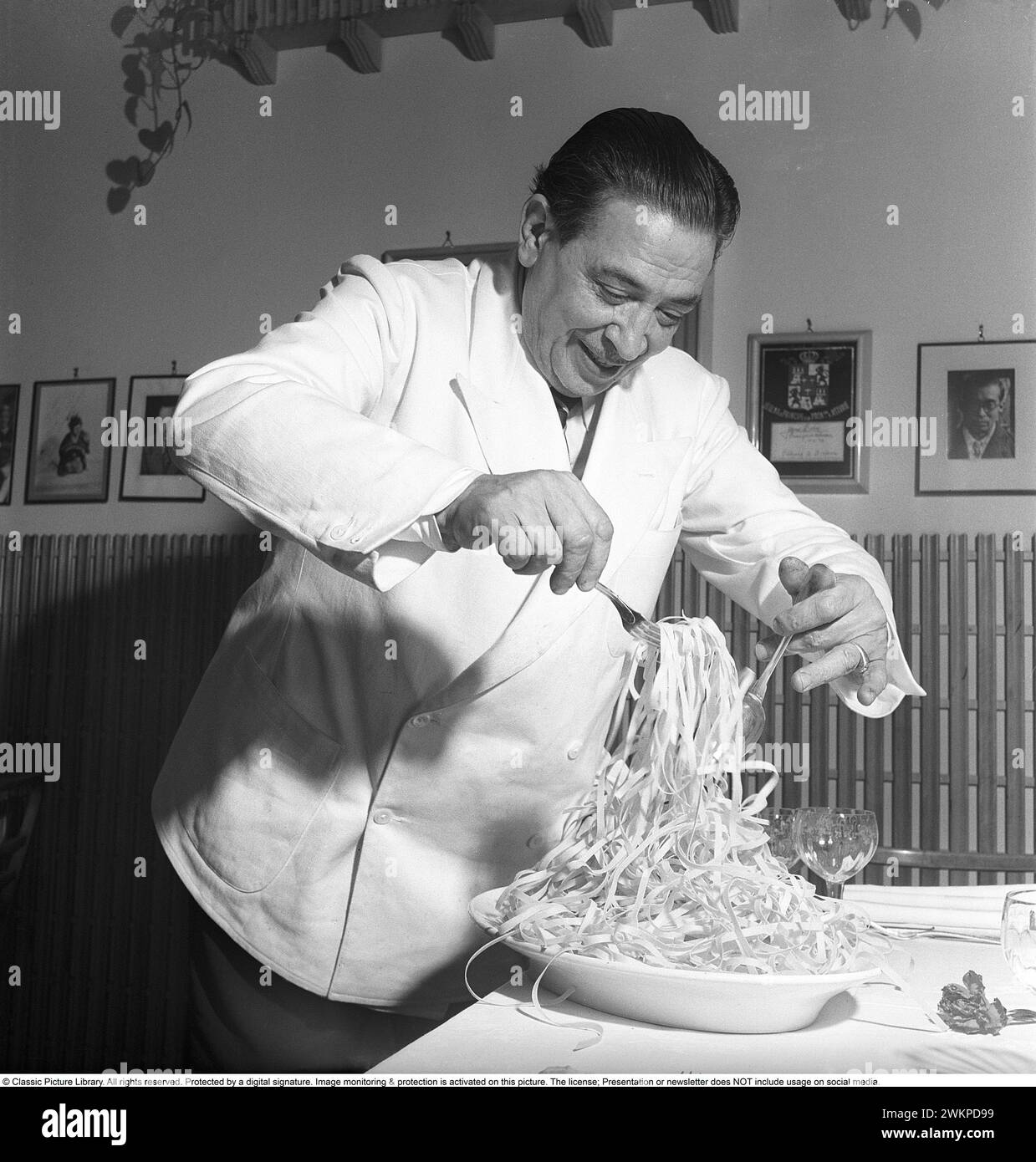 In Italy in the 1950s. A waiter at a table holds the newly cooked pasta and isi preparing it for a guest at the restaurant. Milan Italy 1950. Photo Kristoffersson Ref AY24-1 *** Local Caption *** © Classic Picture Library. All rights reserved. Protected by a digital signature. Image monitoring & protection is activated on this picture. The license; Presentation or newsletter does NOT include usage on social media. Stock Photo
