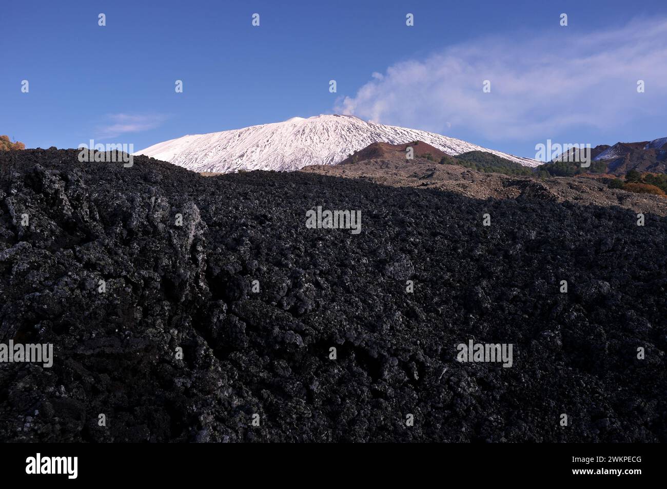 in the shade old lava field and bright Mount Etna snowy in background, Etna Park in Sicily, Italy Stock Photo