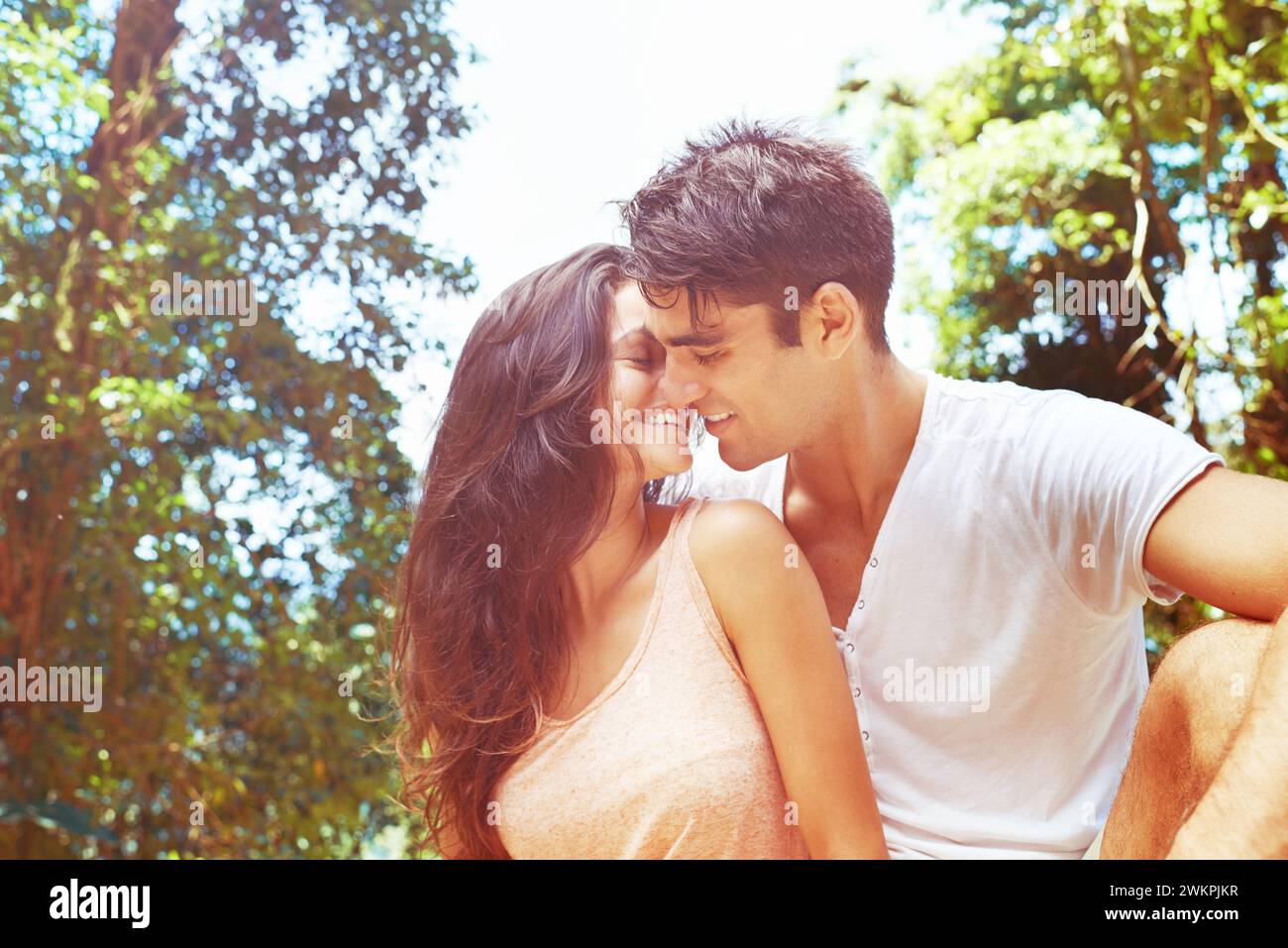 Love, happy and couple kissing in nature for romantic anniversary date ...