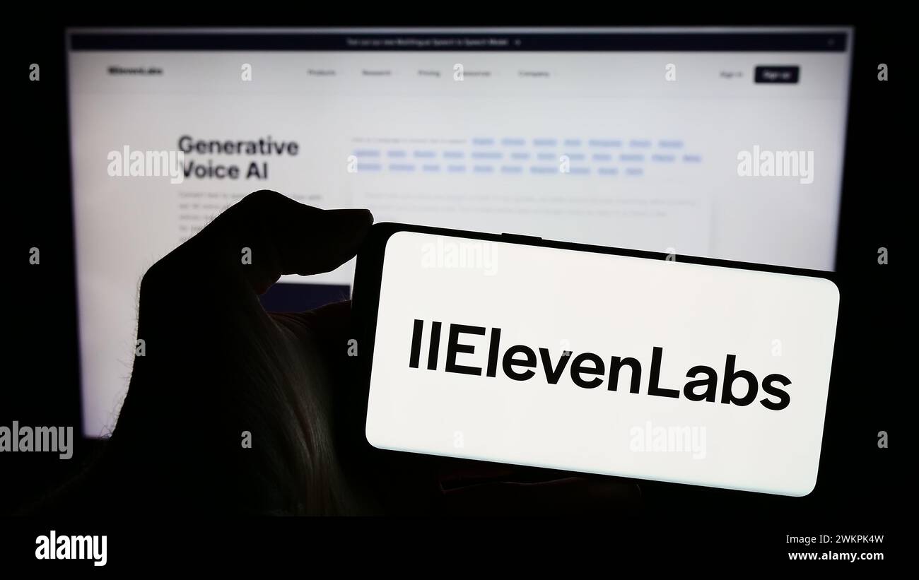 Person holding mobile phone with logo of American artificial intelligence company ElevenLabs Inc. in front of web page. Focus on phone display. Stock Photo