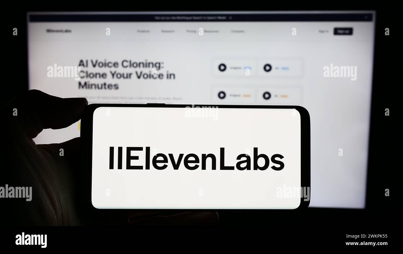 Person holding cellphone with logo of US artificial intelligence company ElevenLabs Inc. in front of business webpage. Focus on phone display. Stock Photo