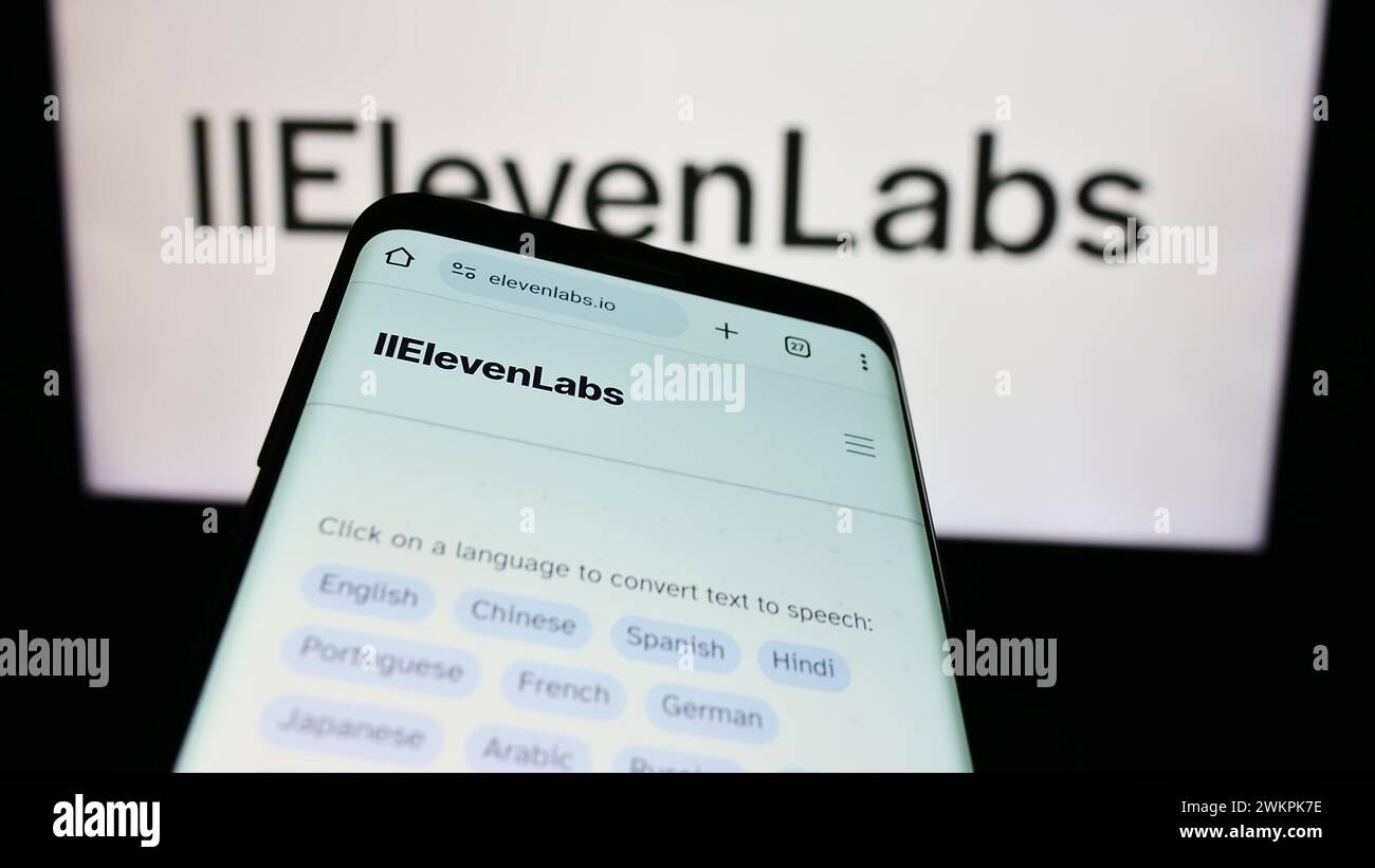 Mobile phone with website of US artificial intelligence company ElevenLabs Inc. in front of business logo. Focus on top-left of phone display. Stock Photo