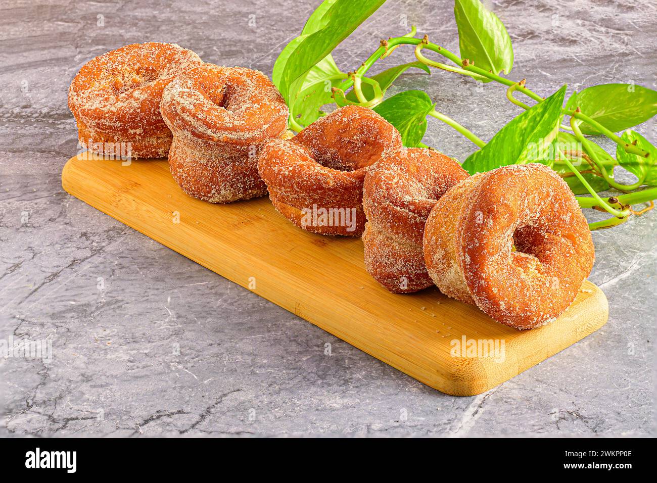The donuts placed on cutting board beside green plants. Stock Photo