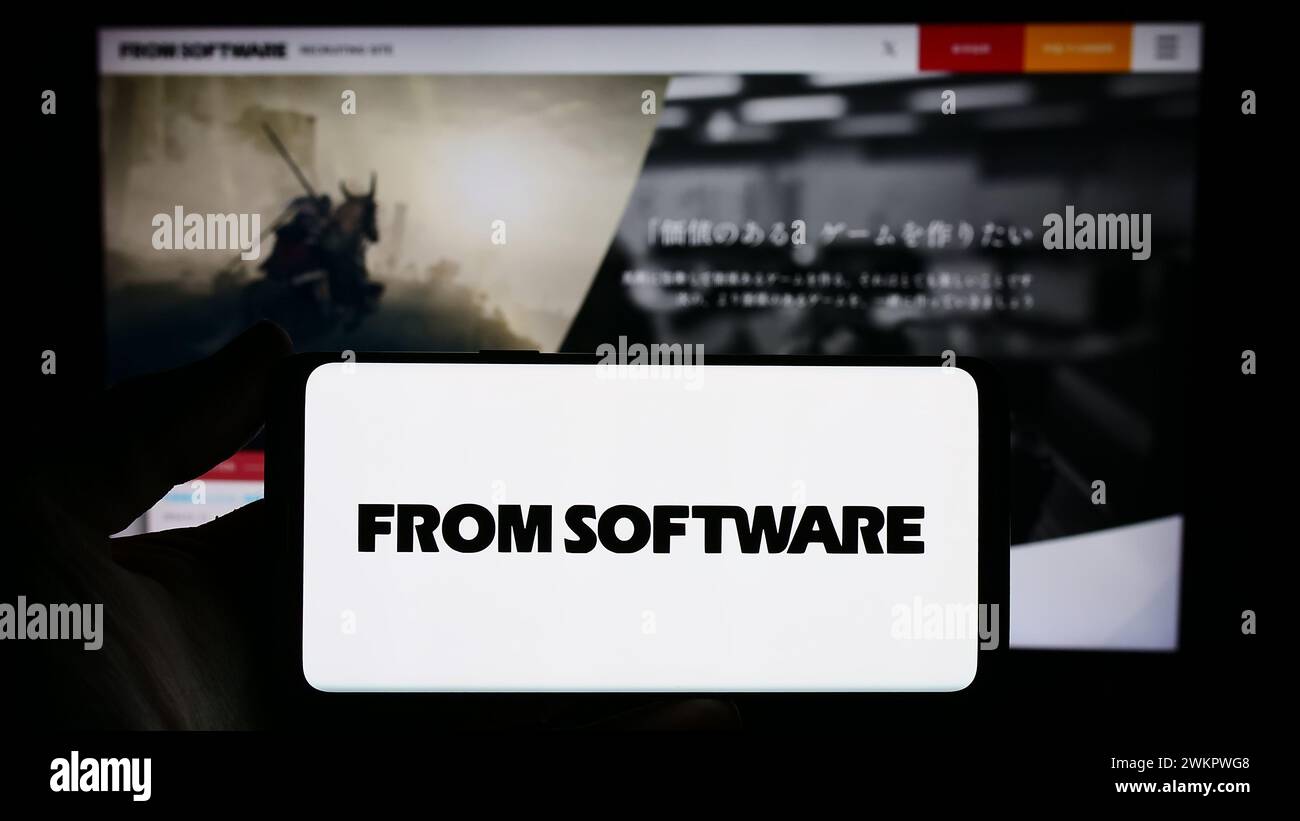 Person holding smartphone with logo of Japanese video games company FromSoftware Inc. in front of website. Focus on phone display. Stock Photo