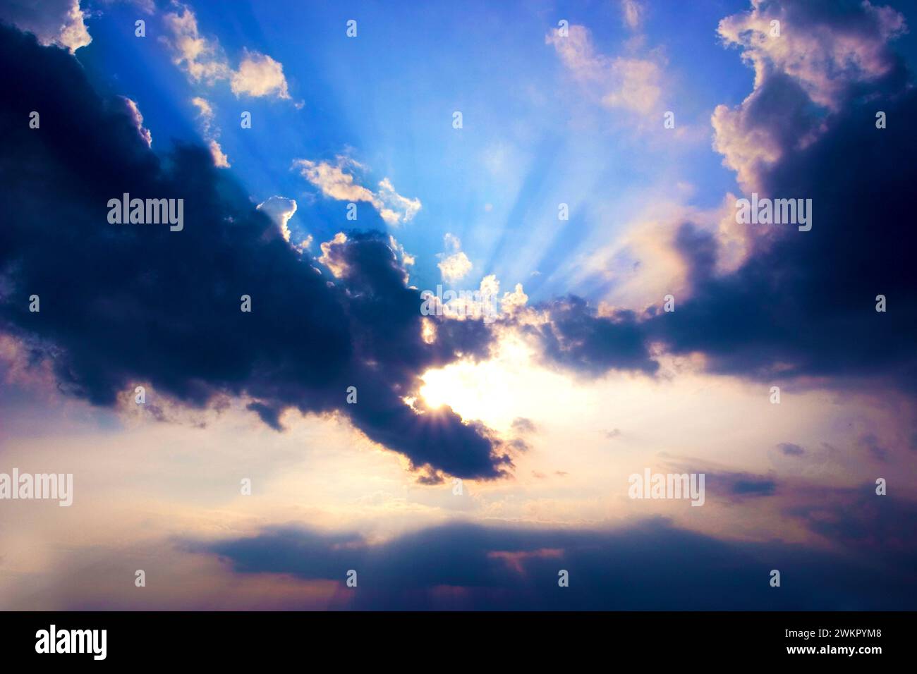 sun behind clouds and sun beams Stock Photo
