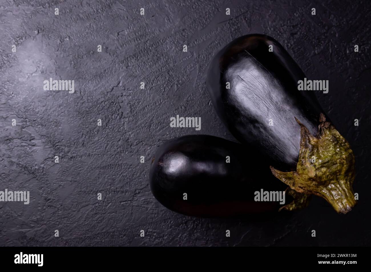 Eggplants on a black table, with low lighting. Stock Photo