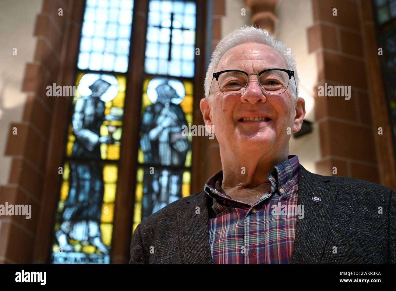 Pfarrer Jeffrey Myers vor dem Kirchenfenster in der evangelischen Alten Nikolaikirche in Frankfurt am Main 06.02.2024. Jeffrey Myers war frueher Stadtkirchenpfarrer an der Alten Nikolaikirche. Seit Herbst 2018 kuemmert sich Myers um die Konzeption von Pilgerwegen und Pilgerprojekten fuer die Einrichtungen der Inneren Mission in Hessen, ein Thema, das ihn schon laenger interessiert, da er bereits ehrenamtlich im Vorstand des Lutherwegvereins mitarbeitet. *** Local Caption *** 00502021 EDITORIAL USE ONLY *** Pastor Jeffrey Myers in front of the church window in the Protestant Old Nikolai Church Stock Photo