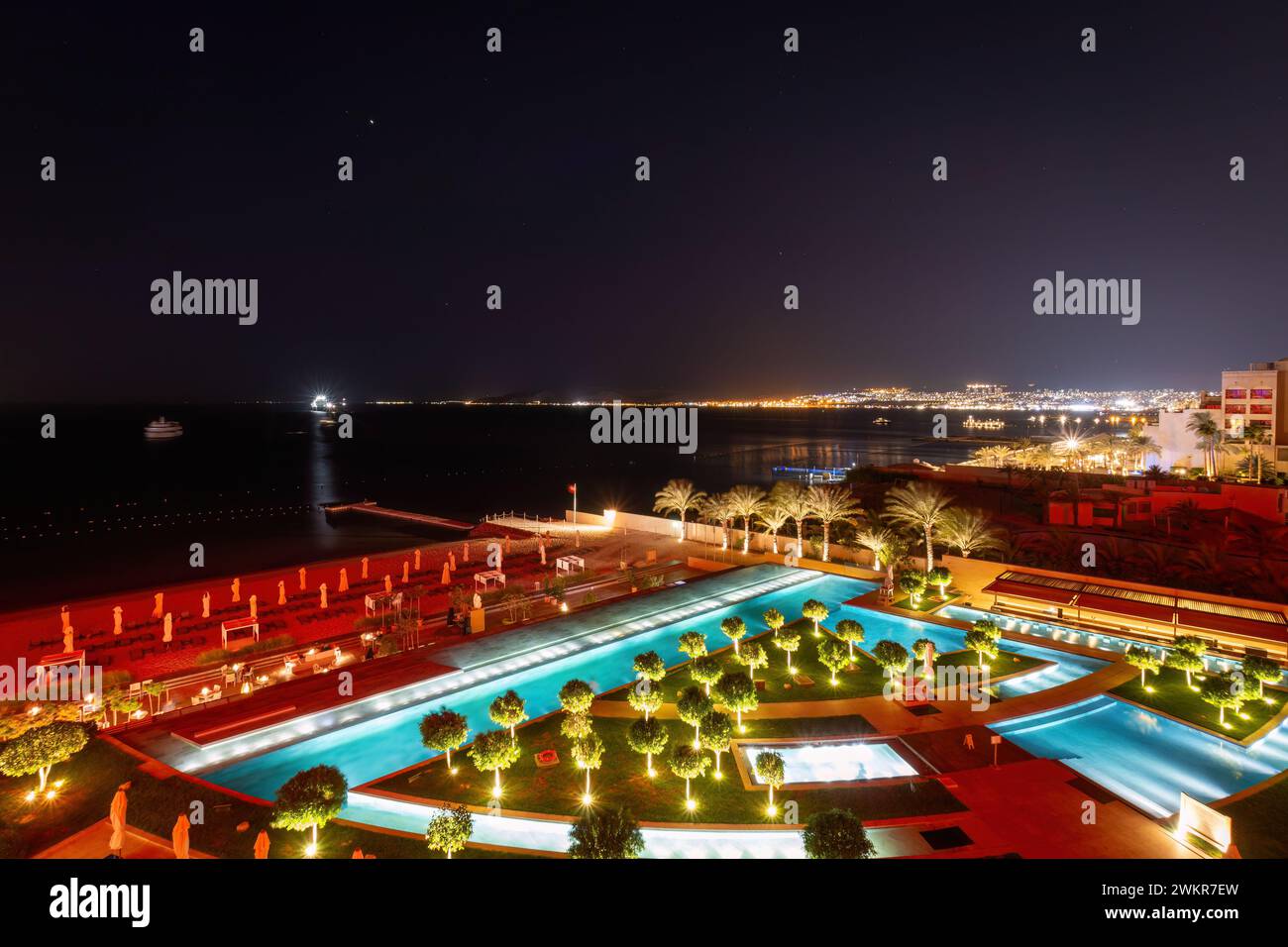 Scenic view of illuminated swimming pool and beach at Gulf of Aqaba in Aqaba, Jordan at night Stock Photo