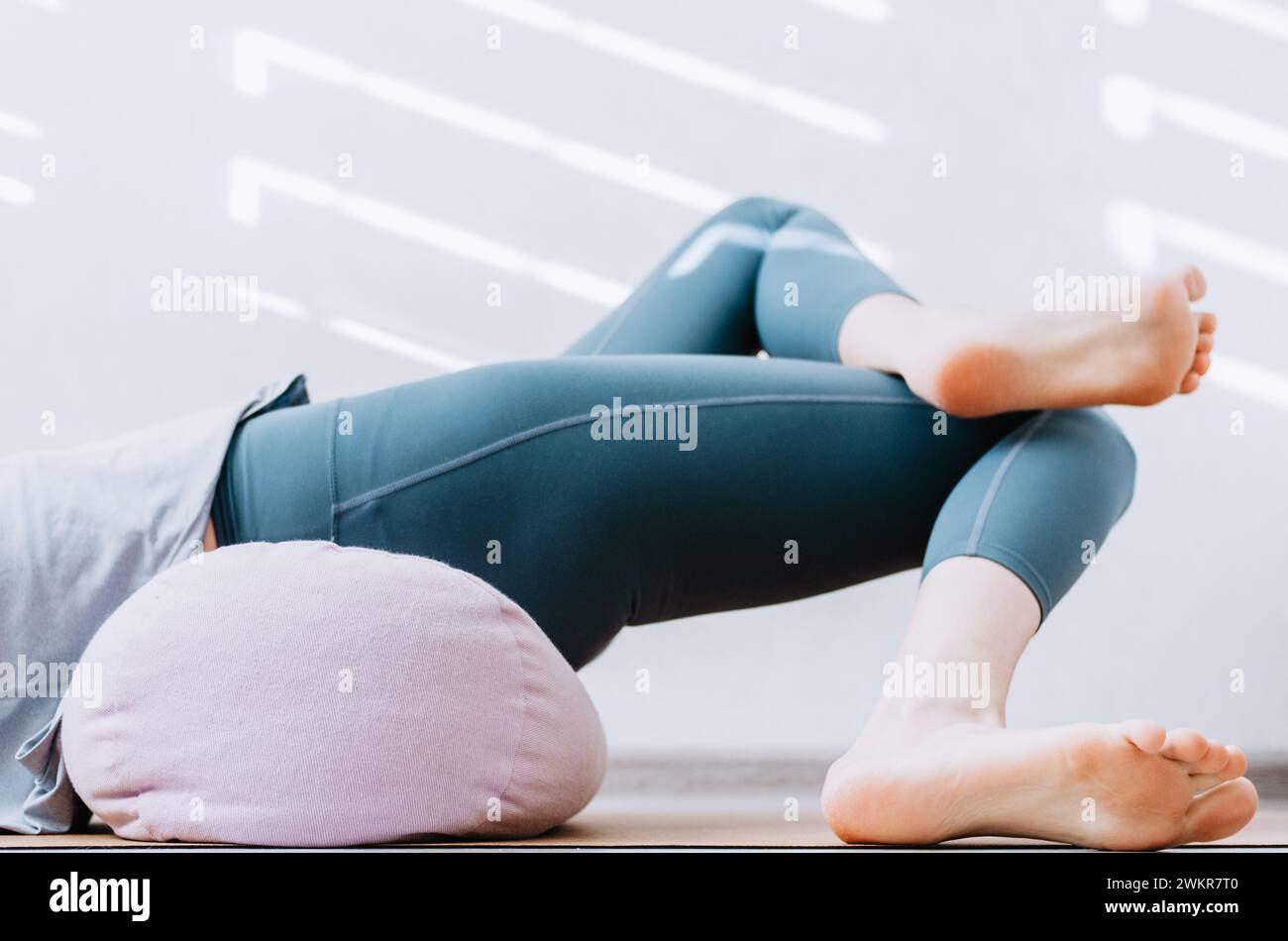 Woman doing yin yoga passive hip stretch exercises on bolster Stock