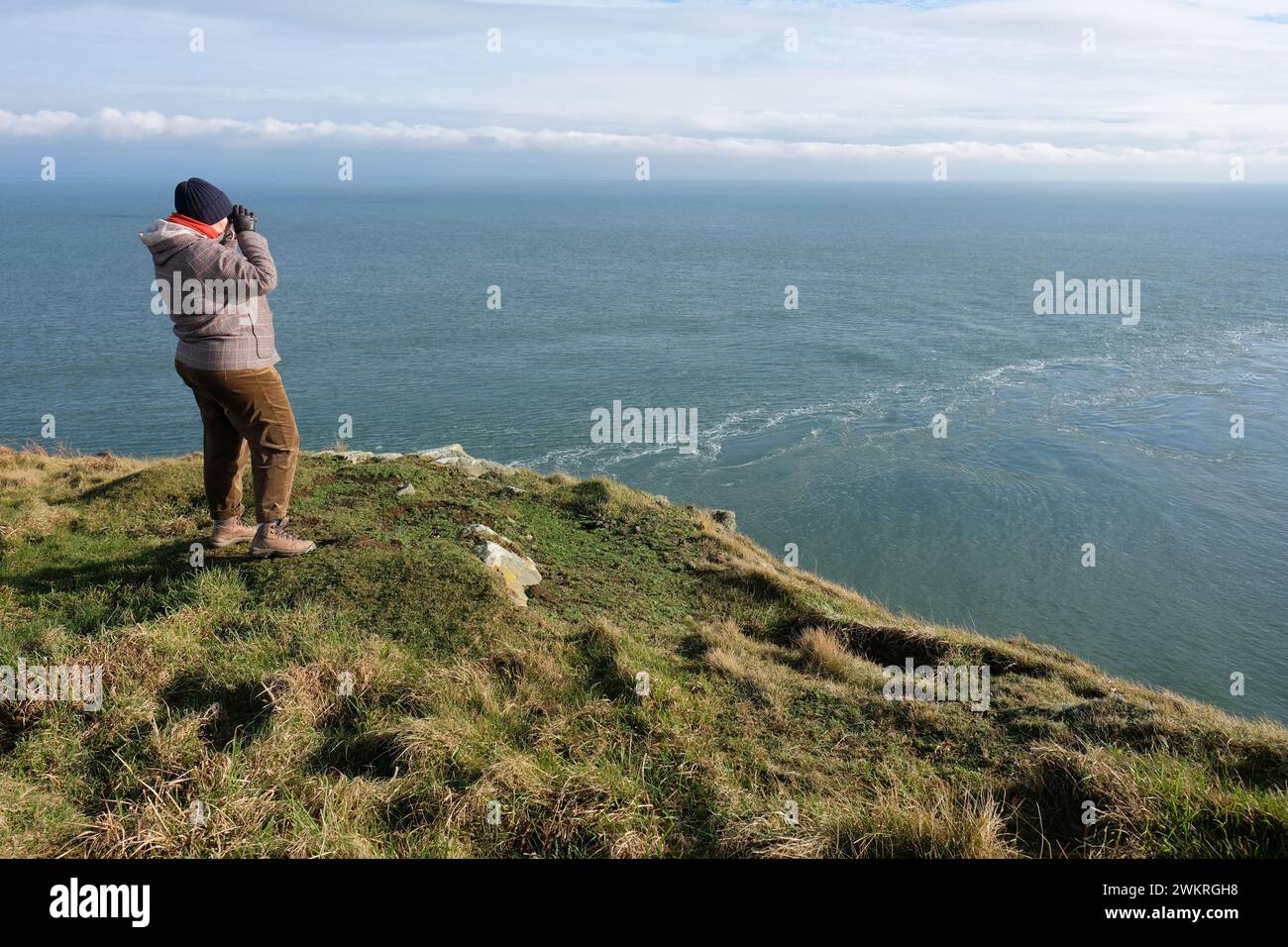 Mull of Galloway a visitor on the cliffs looks for seals and sea birds at Lagvag Point - here the waters of Luce Bay merge with the Irish Sea Stock Photo