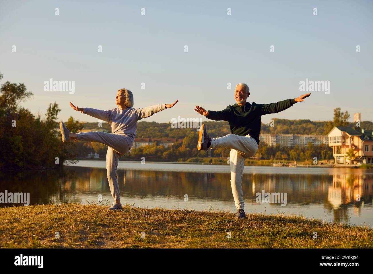 Active sporty senior couple man and woman doing stretching exercising in nature. Stock Photo