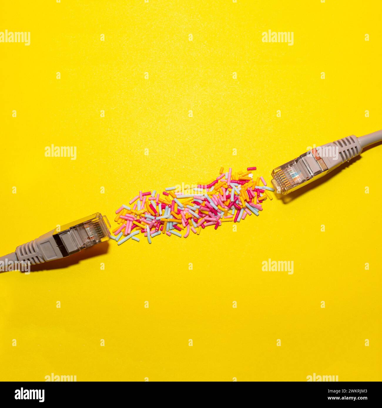 Network cable connected with sprinkles on yellow background. Creative flat lay. Copy space. Stock Photo