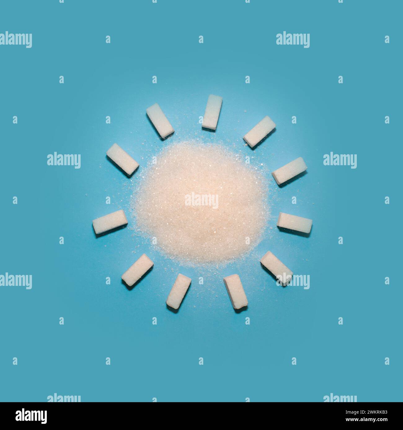 Sugar cubes in the form of a sun on a blue background. Creative food flat lay. Stock Photo