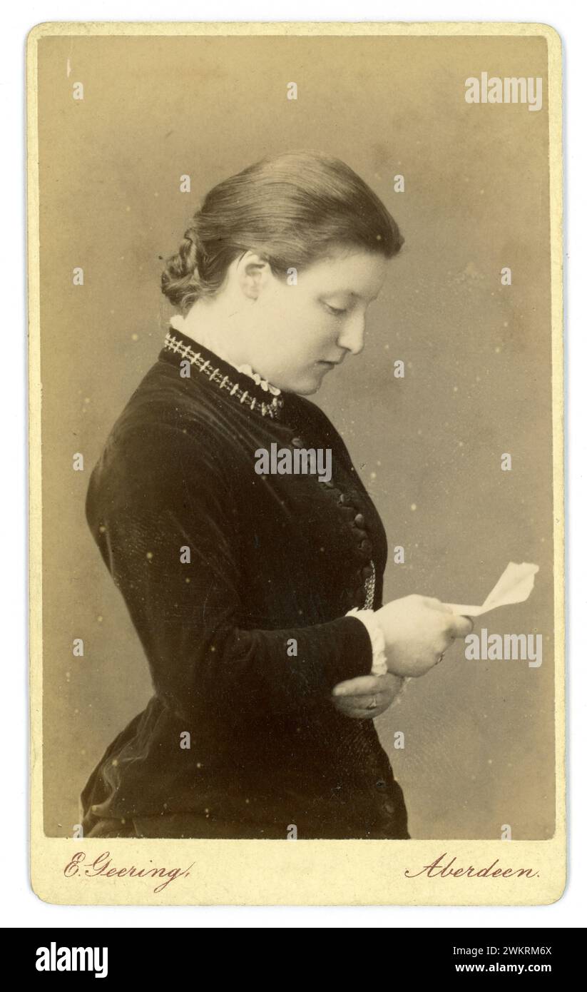 Original Victorian Carte de Visite (visiting card or CDV)- a profile of a young woman called Jessie poses with an open book, From the studio of E. Geering, 10 Union Place, Late of GW Wilson & Co Aberdeen, Scotland from the early 1880s to about 1889, fashion says 1881 Stock Photo