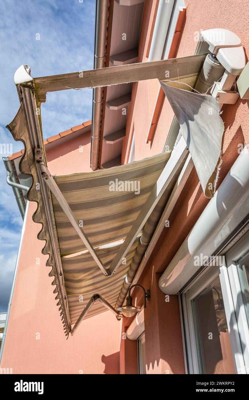 Old, messy, dirty and broken retractable awning installed on family house Stock Photo