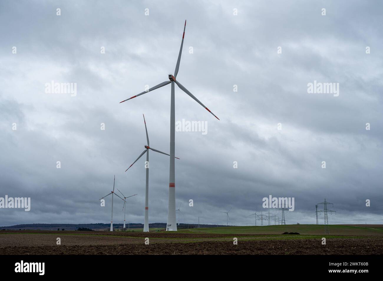 Windräder gegen einen bewölkten Himmel 22.02.24, Limburg: Symbolfoto, Illustrationsbild, Symbolbild, Illustrationsfoto Windräder gegen einen bewölkten Himmel Das Bild zeigt eine Gruppe von Windrädern, die auf einem offenen Feld stehen, mit einem stark bedeckten und bewölkten Himmel im Hintergrund. Diese Szenerie vermittelt die Kraft und Eleganz der Windenergie als erneuerbare Energiequelle, während die Windräder harmonisch in die natürliche Landschaft eingebettet sind. Die düstere Wolkendecke betont die Beständigkeit und Wichtigkeit erneuerbarer Energien in wechselnden Wetterbedingungen. Limbu Stock Photo